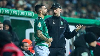 Werders Trainer Ole Werner steht mit seinem Spieler Anthony Jung am Seitenrand.