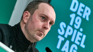 Werder-Trainer Ole Werner sitzt nachdenklich bei einer Pressekonferenz.