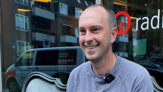 Werder-Trainer Ole Werner sitzt vor dem Gebäude von Radio Bremen.