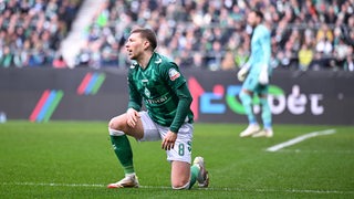 Werder-Profi Mitchell Weiser kniet frustriert auf dem Rasen im Spiel gegen Wolfsburg.