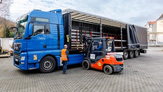 Ein Gabelstaplerfahrer belädt einen Lastwagen.