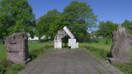 Mehrere Steine vor grünen Bäumen bei einer Gedenkstätte in Blumenthal