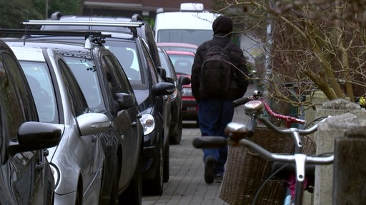 Autos, die auf einem Gehweg parken, sodass kaum Platz für den Fußgänger ist.