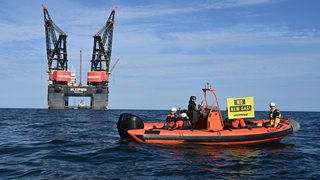 Ein Schlauchboot von Greenpeace mit einem "No new Gas!"-Banner fährt vor der Bohrinsel in Borkum.