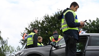 Polizeibeamte kontrollieren an der Grenze Autos.