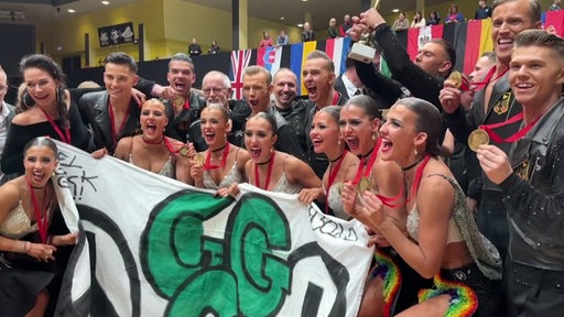 Die Gewinner des Bremer Grün-Gold-Clubs mit einem Banner in der Hand jubelnd in der Gruppe.