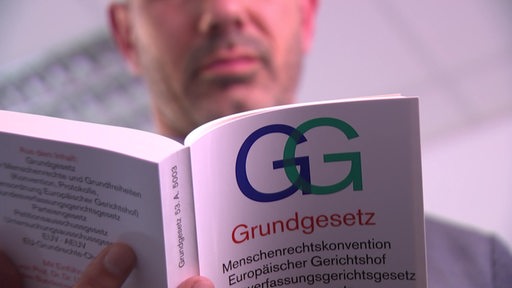 Ein Mann liest in einer gebundenen Ausgabe des Grundgesetzes.