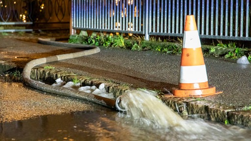 Ein Schlauch pumpt Wasser in einen Abfluss.