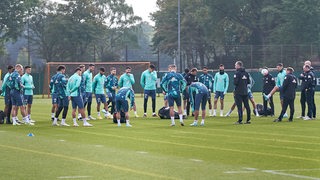 Werders Spieler undTrainer bilden einen Mannschaftskreis auf dem Trainingsplatz.