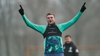 Werder-Stürmer Marvin Ducksch breitet am Rande des Trainings weit seine Arme aus.