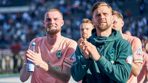 Die Werder-Stürmer Marvin Ducksch und Niclas Füllkrug applaudieren nach dem Sieg in Berlin den mitgereisten Fans.