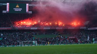 Blick auf den Bayern-Gästeblock im Weser-Stadion, in dem Pyrotechnik abgebrannt wird. Die Tribüne darunter ist teilweise geräumt.