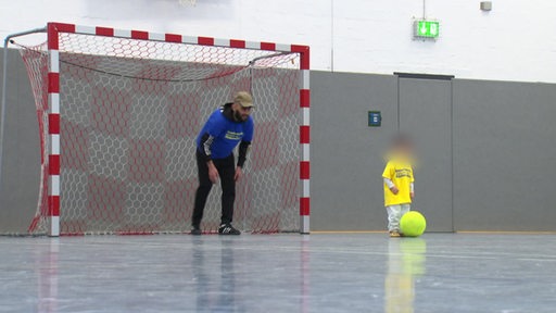 Ein Häftling spielt mit seinem Kind Fussball.