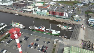 Ein Hafen mit Schiffen und Betrieben, der aus der Vogelperspektive gezeigt wird.