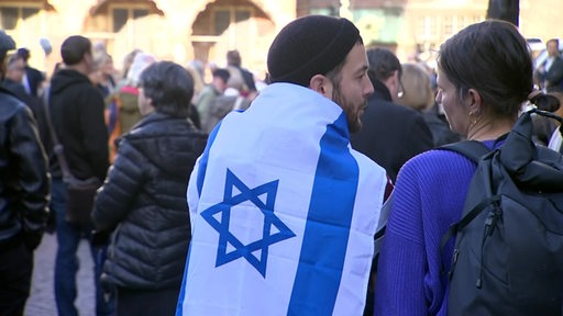 Ein Mann trägt eine israelische Flagge um den Körper.