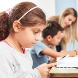 Mädchen schaut auf ein Smartphone im Unterricht einer Grundschule