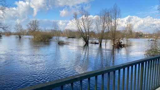 Von einer der kleinen Wümme-Brücke in Borgfeld sind Bäume sichtbar, die unter Wasser stehen.