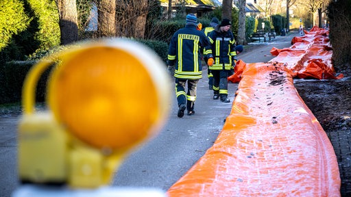 Feuerwehrleute bauen einen mobilen Deich ab. 