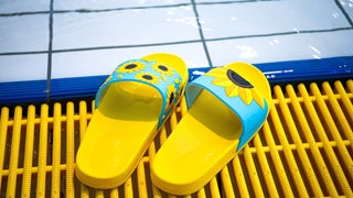 Gelbe Badelatschen liegen am Schwimmerbecken im Horner Bad.