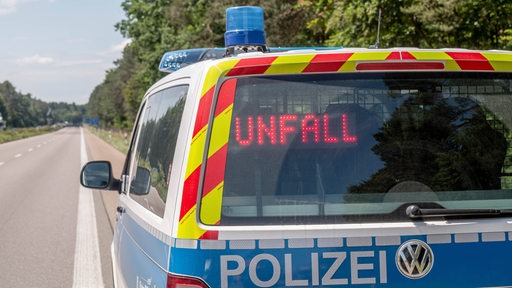 Ein Polizeiwagen steht auf einer leeren Autobahn. Im Rückfenster des Autos steht "Unfall".