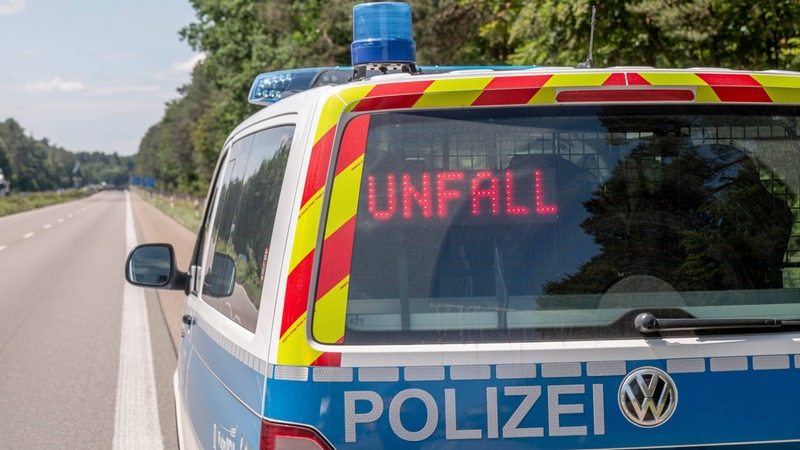 Ein Polizeiwagen steht auf einer leeren Autobahn. Im Rückfenster des Autos steht "Unfall".