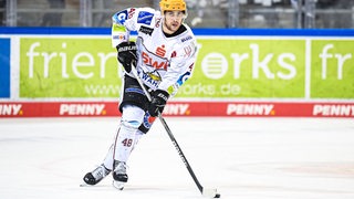 Eishockey-Profi Niklas Andersen von den Fischtown Pinguins führt den Puck mit dem Schläger. 