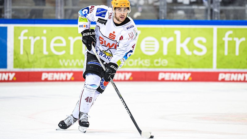 Eishockey-Profi Niklas Andersen von den Fischtown Pinguins führt den Puck mit dem Schläger. 