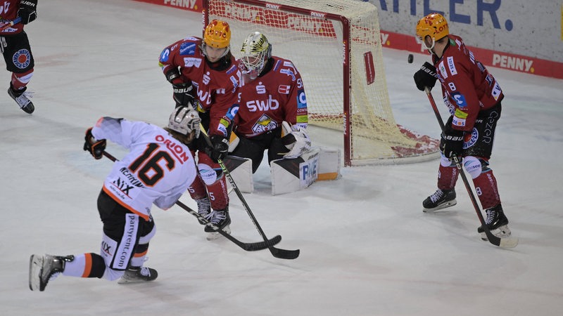 Drei Spieler der Pinguins verteidigen das Tor, ein Spieler der Löwen zielt auf das Tor.