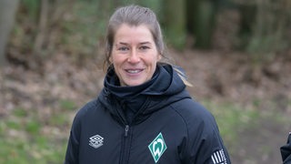 Marie-Louise Eta lächelnd auf dem Weg zum Training in die Kamera.