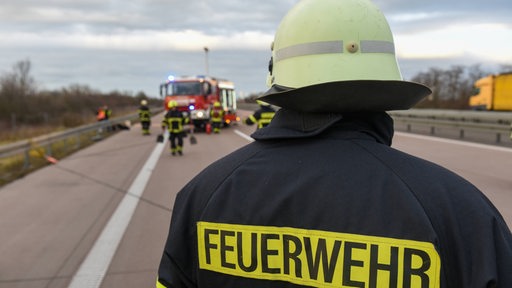 Ein Feuerwehrmann blickt auf eine Unfallstelle