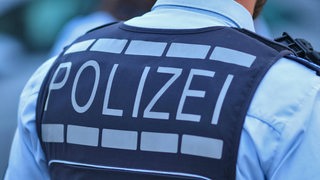 Zu sehen ist ein Polizist, der eine schusssichere Weste trägt.