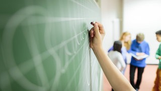 Ein Schüler schreibt an eine Tafel. 