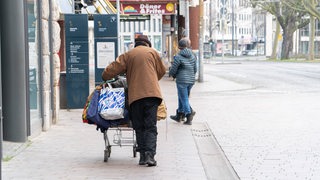 Ein obdachtloser Mann schiebt sein Hab und Gut in einem Einkaufswagen (Archivbild)