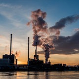 Industriegelände am Wasser mit rauchenden Schornsteinen