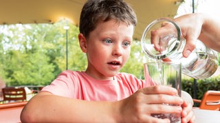 Ein Kind bekommt ein Glas Wasser eingeschenkt