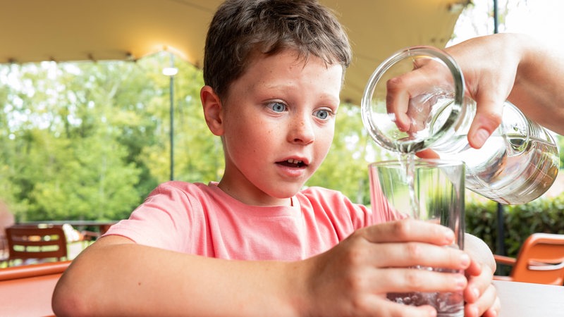 Ein Kind bekommt ein Glas Wasser eingeschenkt