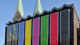 Das Gebäude der Bremischen Bürgerschaft, deren Fenster in den Farben Schwarz, Rot, Grün, Lila, Gelb und Blau eingefärbt sind.