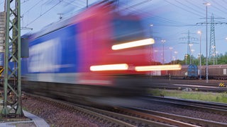 Ein Güterzug fährt abends auf einem Rangierbahnhof vorbei