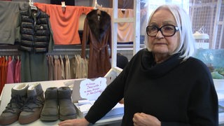 Eine Frau steht in einem Modegeschäft zwischen Jacken und Schuhen