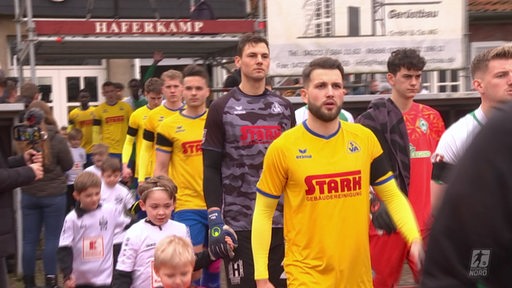 Die Spieler von Atlas Delmenhorst und Werder Bremen II betreten den Platz.