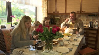 Ukrainischer Soldat sitzt mit seiner Frau und Kindern am Tisch und frühstückt