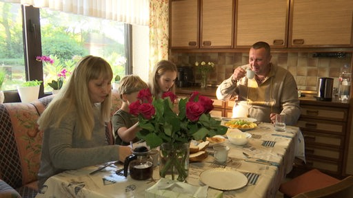 Ukrainischer Soldat sitzt mit seiner Frau und Kindern am Tisch und frühstückt