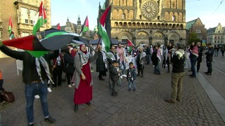 Menschen schwenken auf dem Bremer Marktplatz Palästina-Flaggen.