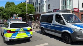 Zwei Polizeiwagen stehen vor einem Supermarkt.