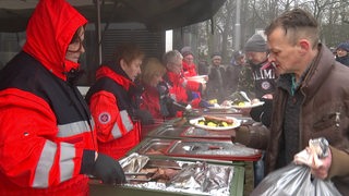 Die Johanniter geben eine warme Mahlzeit an Bedürftige aus.