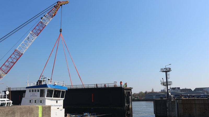 Ein Schiff hebt mit einem Kran einen Teil der Kaiserschleuse an