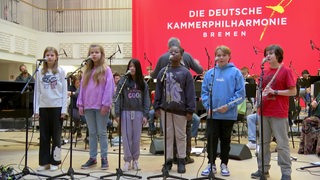 Kinder stehen gemeinsam mit der Kammerphilharmonie auf der Bühne.