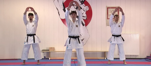 Drei Männer in traditionellen Karate Uniformen stehen in einem Dojo