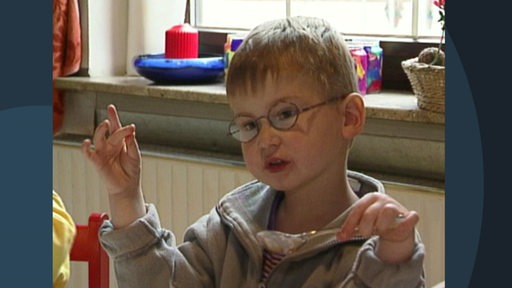 Ein Kind sitzt im Kindergarten und ist am essen.