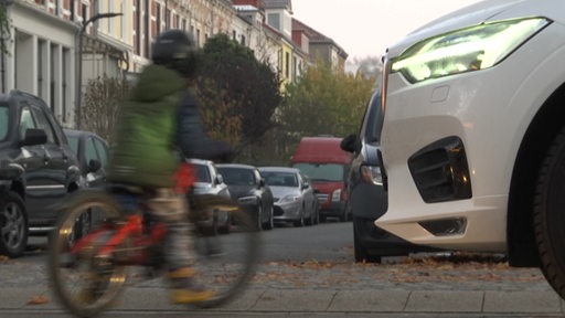 Ein Kind fährt vor einem Auto über die Straße